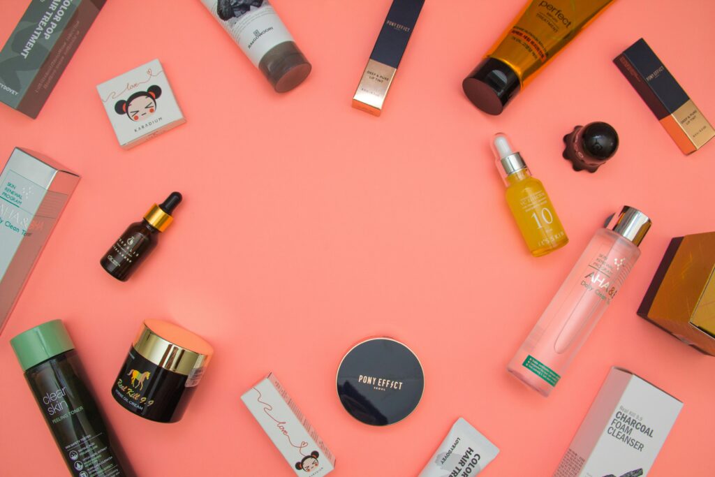 Assorted skincare and beauty products in flat lay on a vibrant pink backdrop.